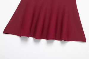 Macro detail of wine red knit fabric showing fine texture and wavy hemline drape