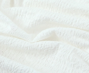 Detailed macro view showing the textured seersucker fabric of the white summer dress