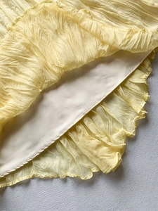Detailed view of the yellow pleated fabric and smooth lining of the long skirt