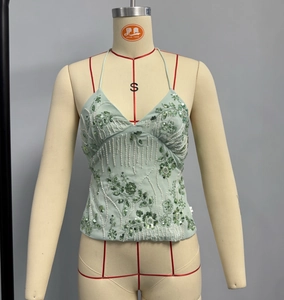 Detail of light green sequin halter top with white bead floral embroidery and deep V-neck