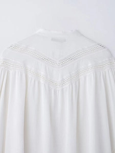 Detailed close-up of intricate hollow lace stitching on a white bohemian style blouse
