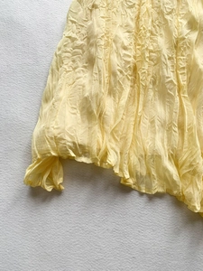 Close-up of light yellow crinkled texture fabric showing elegant pleats and drape detail