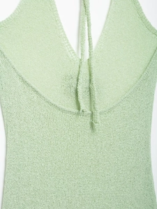 Close-up of the delicate light green crochet knit fabric and halter tie detailing