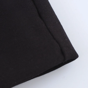 Gros plan des coutures du tissu noir et détail de l'ourlet de la robe courte