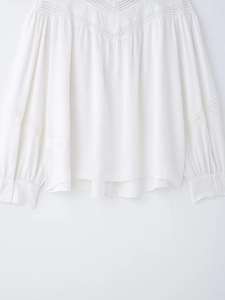 Detailed close-up of V-neck lace hollow stitching on white bohemian style women's shirt