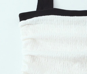 Detailed close-up of the black wide strap and white shirred fabric texture on the dress