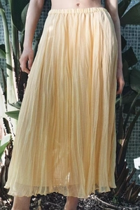 Detailed texture of pleated yellow maxi skirt featuring light elastic waist and flowing fabric