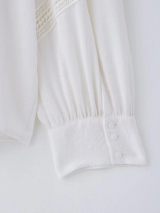 Close-up of white long sleeve shirt cuff with lace inserts and three round buttons