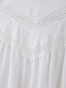 Close-up of intricate double V-shaped lace embroidery on white cotton fabric