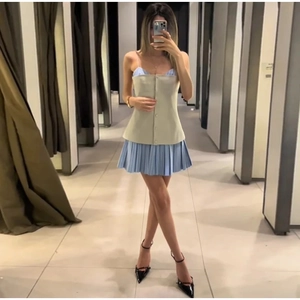 Full-body shot of a chic beige buttoned vest paired with a light blue pleated mini skirt