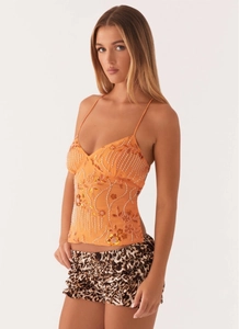 Detail of bright orange camisole with white beads and sequin floral patterns