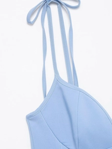 Détail d'une robe bleu clair montrant de fines bretelles et un nœud délicat au décolleté
