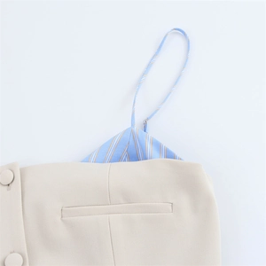 Detail of beige fabric with matching buttons and blue yellow striped camisole dress