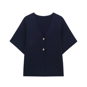 Detailed close-up of dark blue knit top with two gold metallic buttons and a V-neckline
