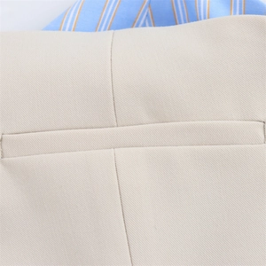 Detailed close-up of beige twill fabric texture and pocket stitching of the dress