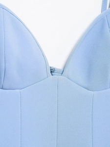 Détail d'une robe bleu clair montrant le col en V et la fermeture à agrafe en métal