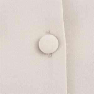 Close-up of a twill fabric texture and matching fabric-covered button on the dress