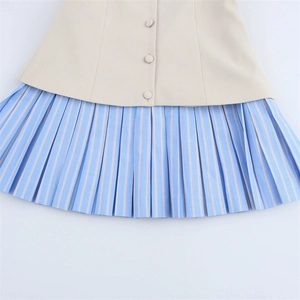 Detailed view of beige poplin waist with buttons and blue striped pleated hemline