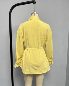 Detail view showing back of yellow long-sleeve blouse with waist drawstring and textured fabric