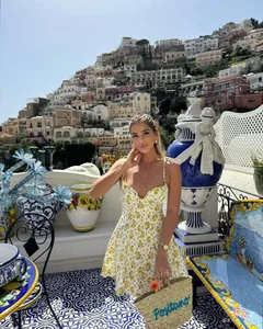 Close-up of yellow floral poplin dress with thin straps and a Positano straw tote bag