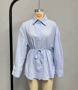 Detail view of light blue linen shirt featuring adjustable drawstring waist and button closure