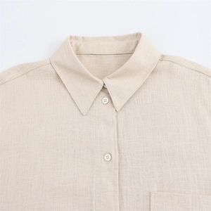 Detail of beige linen shirt showing neat collar structure and small round buttons