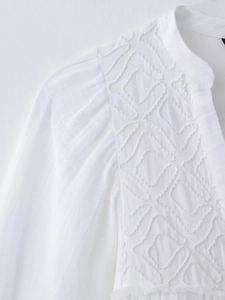 Detailed view of white cotton-linen blouse featuring mandarin collar and 3D embroidery