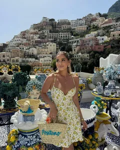 Detail of yellow floral poplin mini dress paired with Positano straw woven beach bag