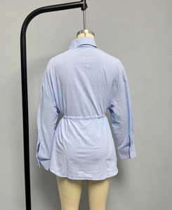 Detail view of light blue shirt showing waist-cinching stitching and curved hemline