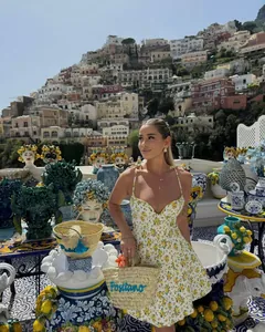 Detail of floral summer dress with blue Positano embroidered straw handbag on a terrace