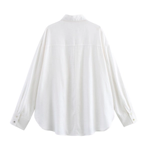 Detail view of the white linen shirt's back pleat, curved hem and fabric texture