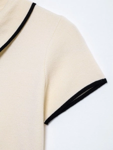 Detailed view of the fine cream knit fabric with contrasting black ribbed edge trim