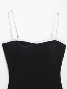 Detail of the black bodysuit with white contrast straps and silver metal buckles