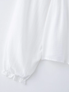 Detail of white blouse featuring ruffled elastic cuffs and textured vertical stripe fabric