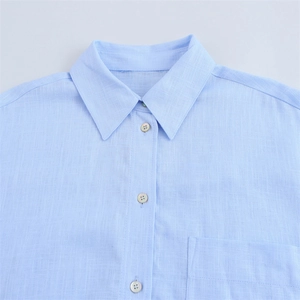 Detail of light blue linen shirt featuring a classic collar and functional chest pocket