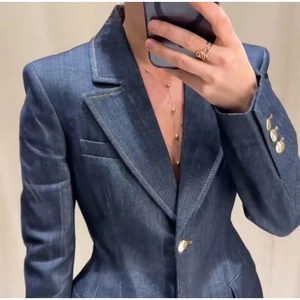 Détail du blazer en denim bleu marine avec revers en pointe et boutons dorés aux manches