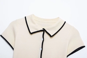 Detail shot of the polo collar and button placket on a white knit set with black trim