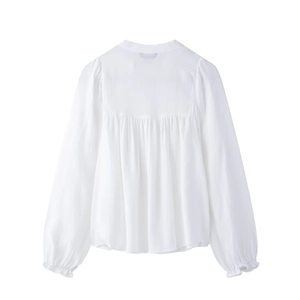 Detail view of white long-sleeve blouse with pleated back and elastic ruffled cuffs