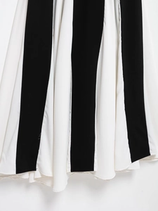 Dettaglio di un elegante vestito lungo a righe verticali bianche e nere in chiffon fluido