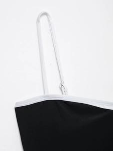 Detail of black bodysuit with white contrast trim and adjustable metal strap buckle