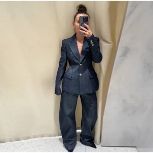 Détail d'un blazer en denim bleu foncé à boutons dorés avec un pantalon large assorti
