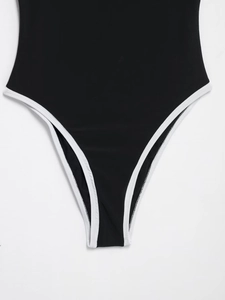 Detail of black bodysuit with white contrast piping and high-cut leg elastic fabric