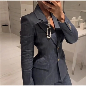 Détail de la taille ajustée et des boutons dorés sur un blazer en denim bleu foncé