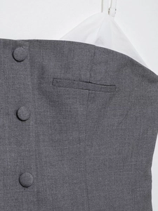 Detail of dark grey pleated dress with fabric buttons and small decorative pocket