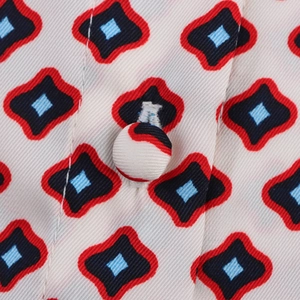 Macro detail of geometric print fabric featuring a matching fabric-covered button and sewing