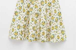 Detailed macro view of yellow floral print on ivory poplin fabric dress with pleated hem