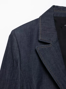 Détail d'une veste en denim bleu foncé avec surpiqûres marron contrastées sur le col à revers