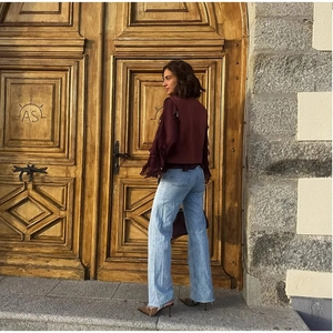 Detail of dark red ruffled chiffon top paired with frayed high-waist wide-leg jeans
