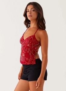 Détail du caraco à paillettes rouges avec broderies de perles blanches et fines bretelles