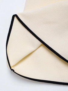 Detail of cream rib-knit fabric with elegant black contrast piping and smooth stitching